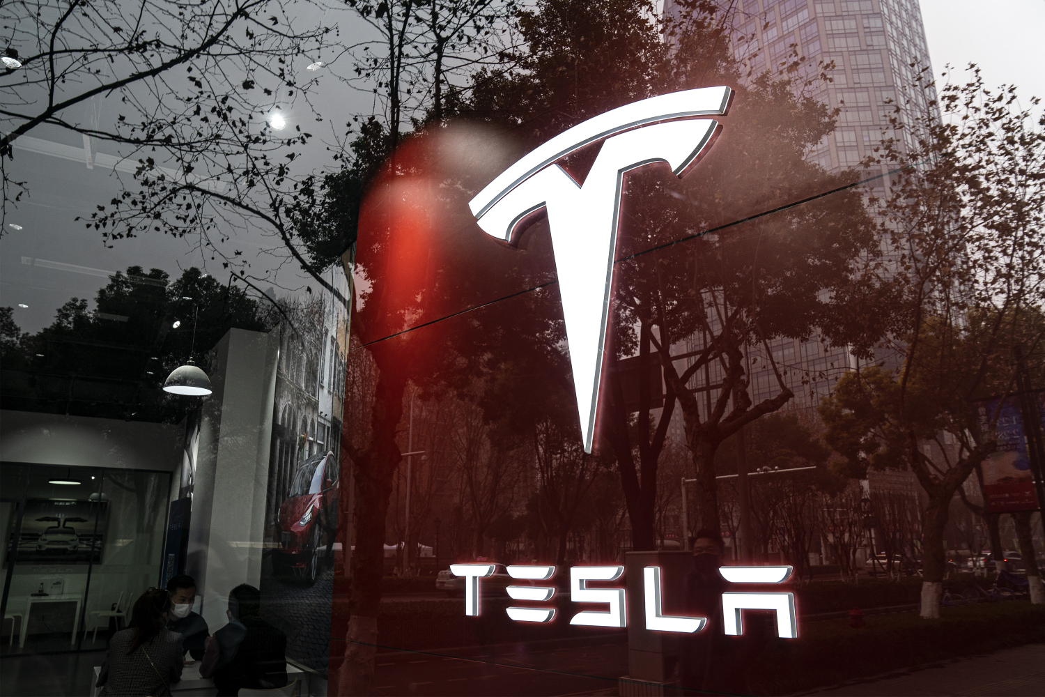 An illuminated Tesla sign seen from outside