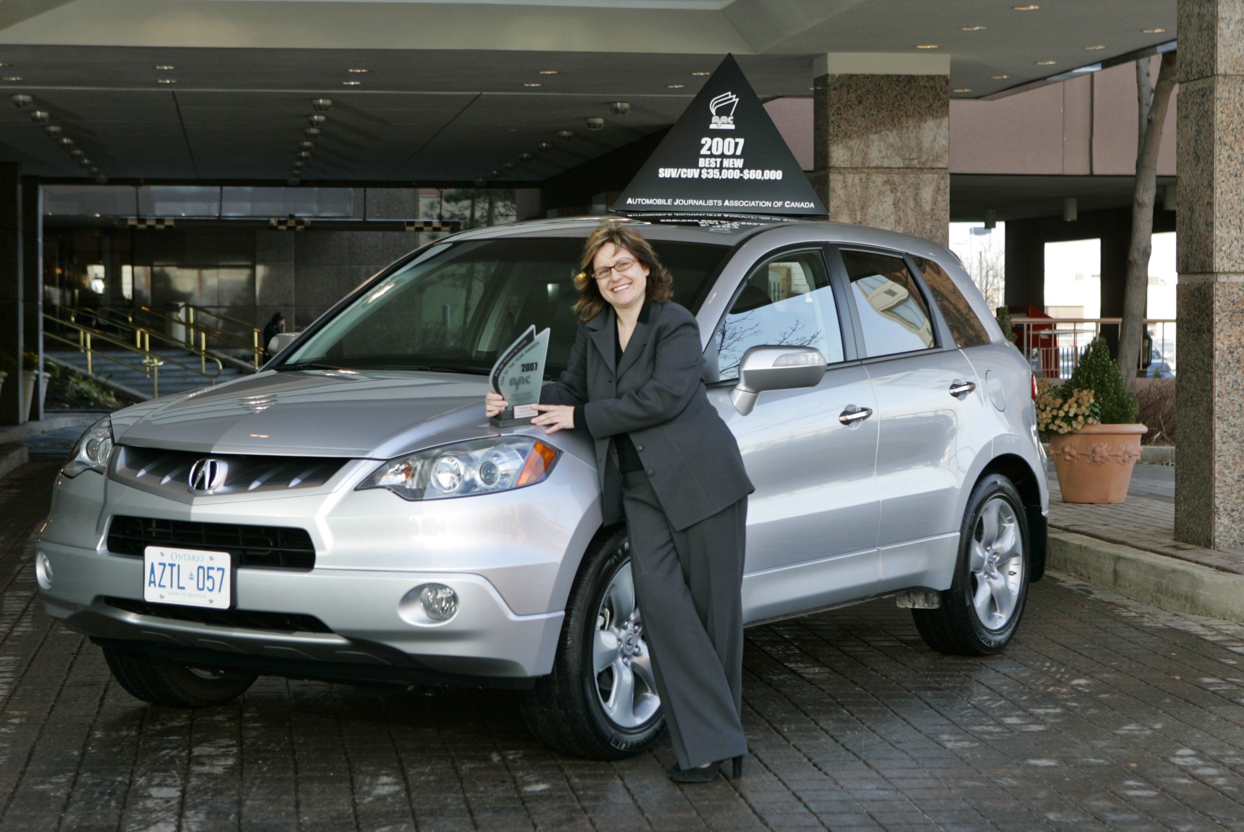 A woman posing next to a parked Acura RDX