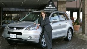 A woman posing next to a parked Acura RDX