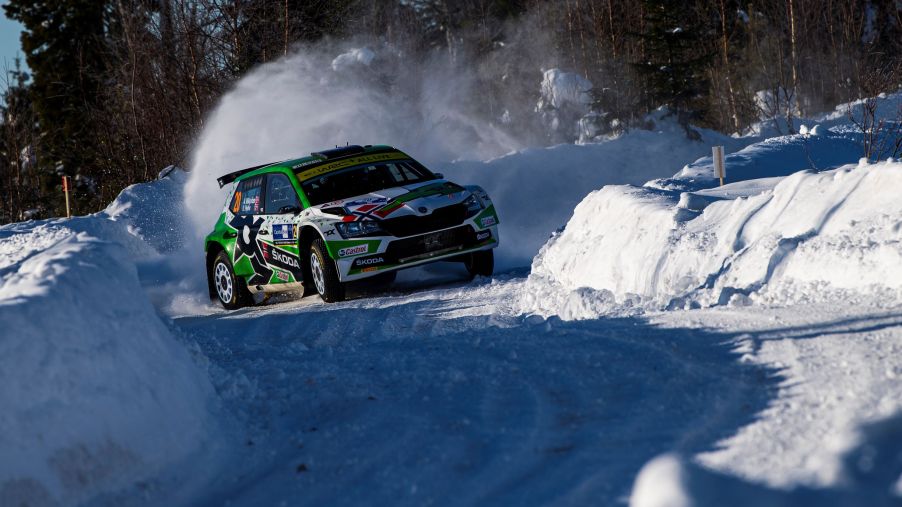 A green-and-white WRC Skoda Fabia Evo drifts through a turn at the snow-covered 2021 Artic Rally Finland