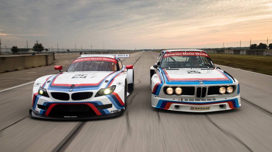 A new BMW M car and heritage BMW M car, both white with iconic red, purple and blue stripes