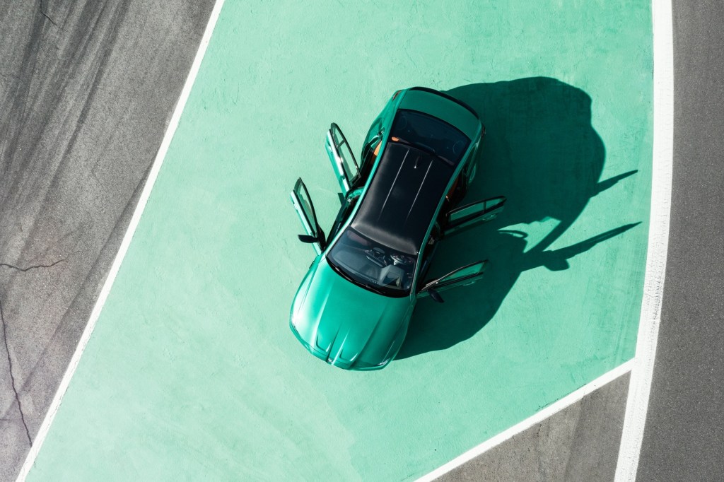A top view of an emerald green 2021 BMW M3 on a green painted pavement