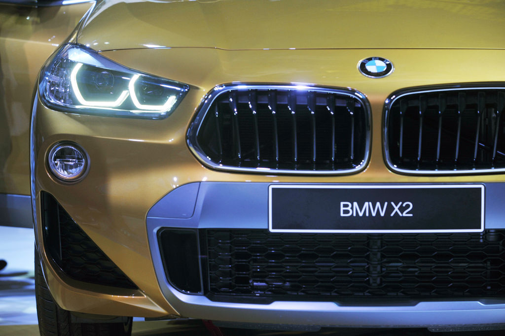 The front end of a gold bmw x2 up close