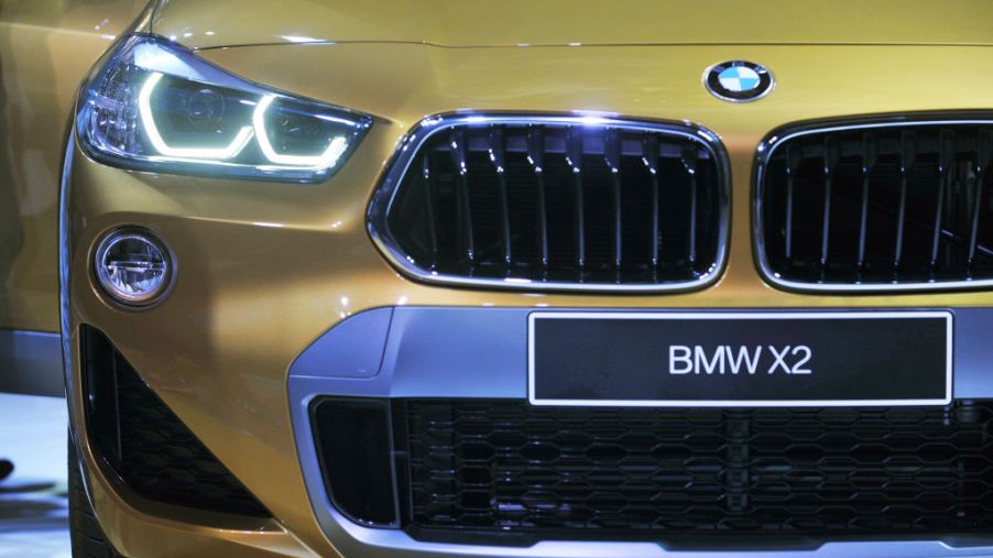 The front end of a gold bmw x2 up close