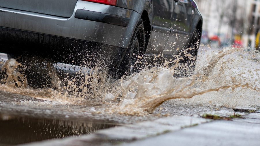 A car drives through a large puddle and potentially hydroplaning