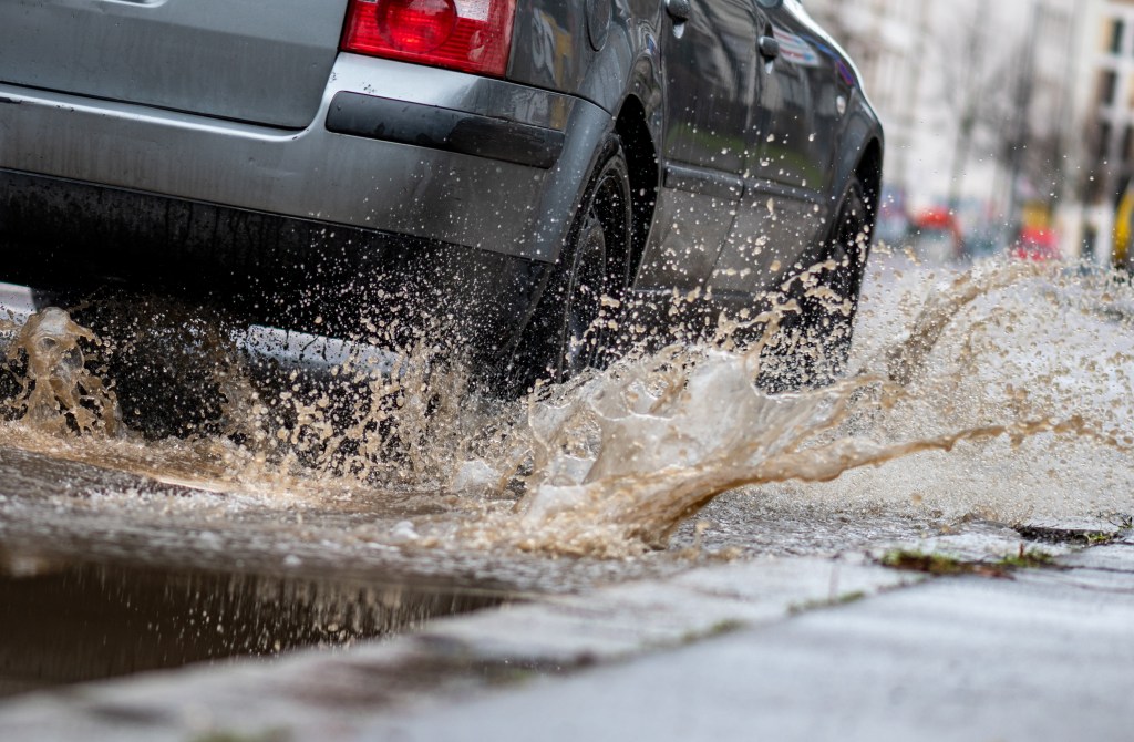 A car drives through a large puddle and potentially hydroplaning