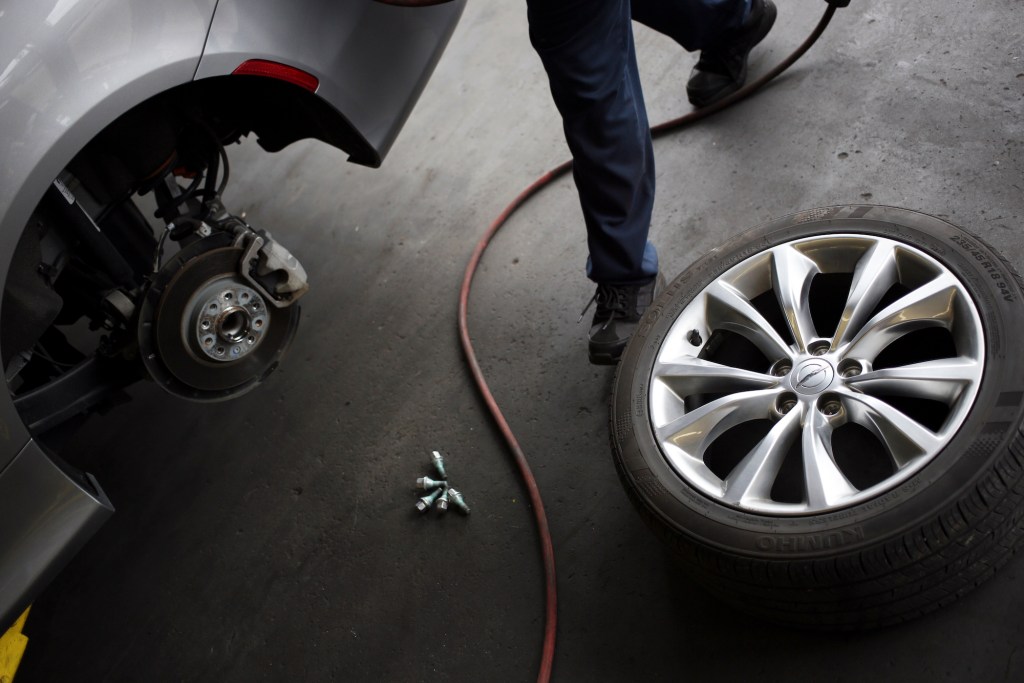 A car mechanic prepares to perform a tire rotation on a customer vehicle at a Pep Boys Company auto repair and service center in Clarksville, Indiana, on Wednesday, June 3, 2015.