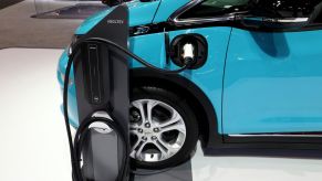 A bright blue chevy bolt on display with a charging station