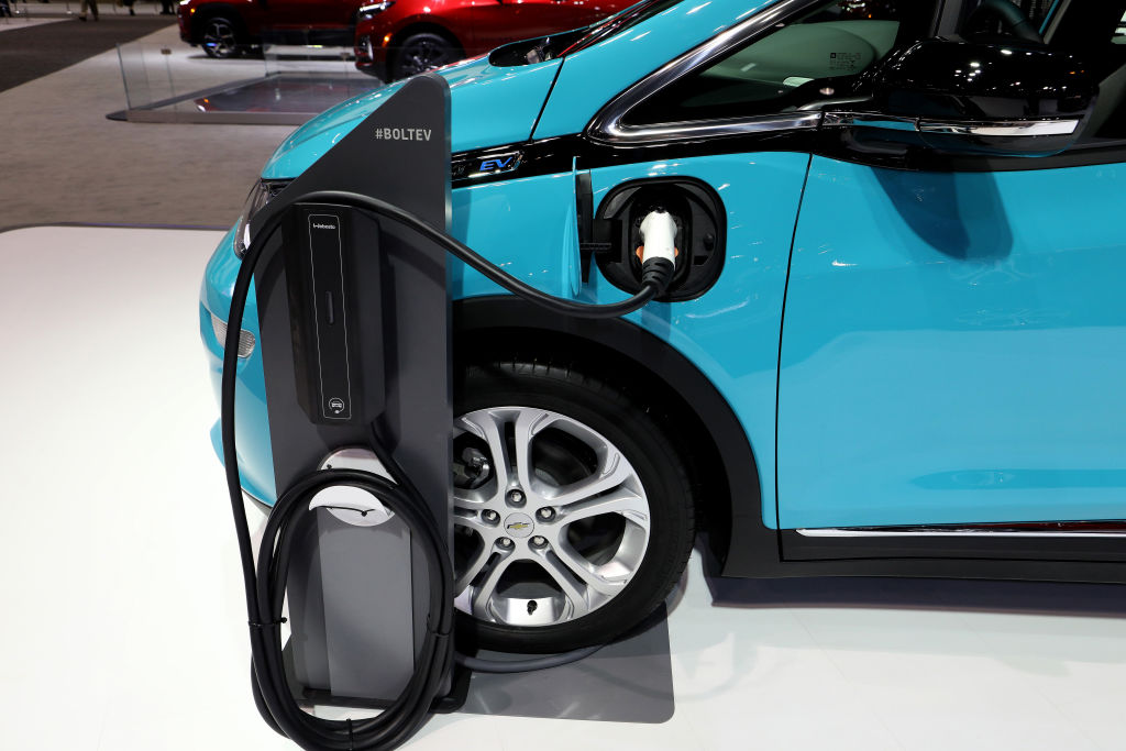A bright blue chevy bolt on display with a charging station