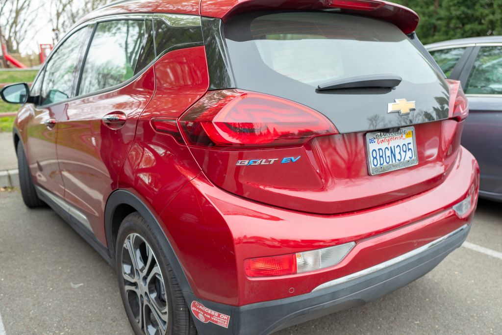 View from behind of red Chevrolet Bolt electric car, with logo and California DMV clean air access okay decal visible