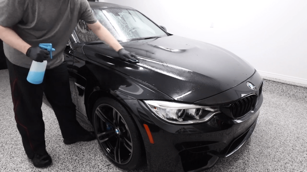 A detailer performs a clay bar treatment on a BMW
