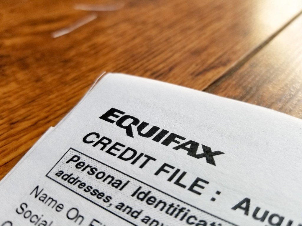 Close-up of the upper corner of a consumer credit report from the credit bureau Equifax, with text reading "Credit File" and "Personal Identification" on a light wooden surface on September 11, 2017