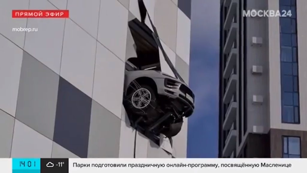 Crashed Porsche Macan hangs off the side of a building teetering on the edge