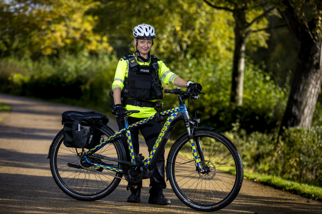 A police officer holding a new electric bike in a park