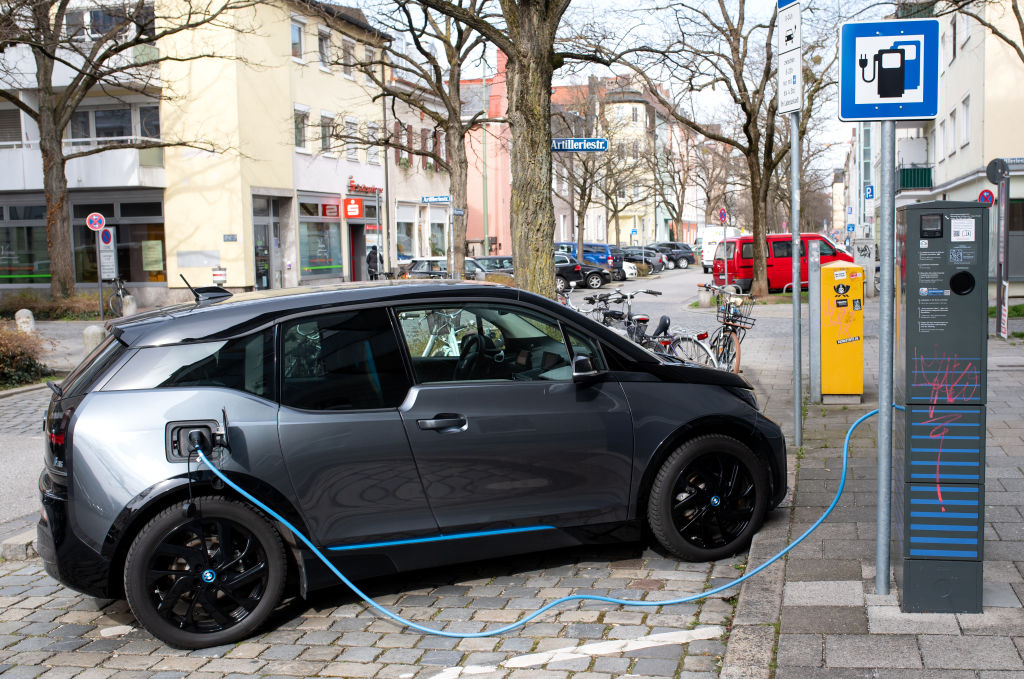 A gray BMW i3 plugged into a charging station