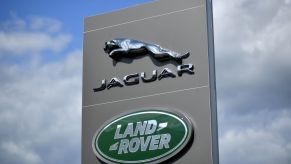 A tall Jaguar/Land Rover sign against a blue sky with white clouds
