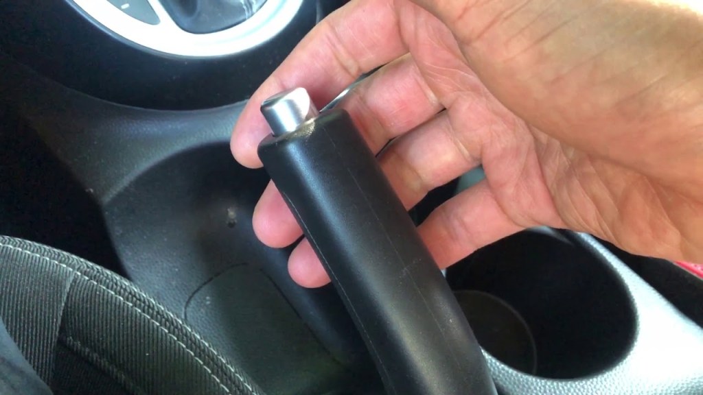 A picture of a hand Pulling the parking brake in a Kia Soul