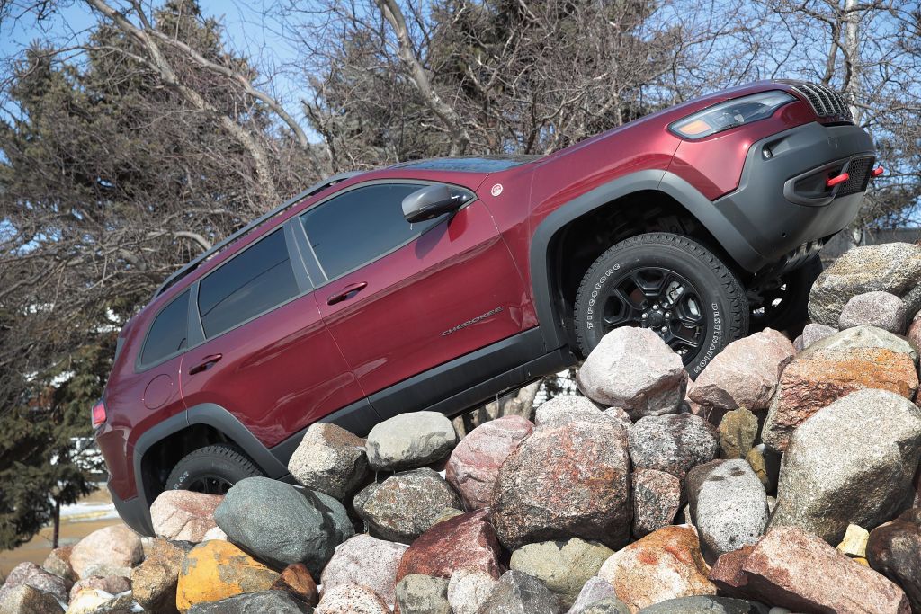 A red Jeep Cherokee driving up a pile of rocks