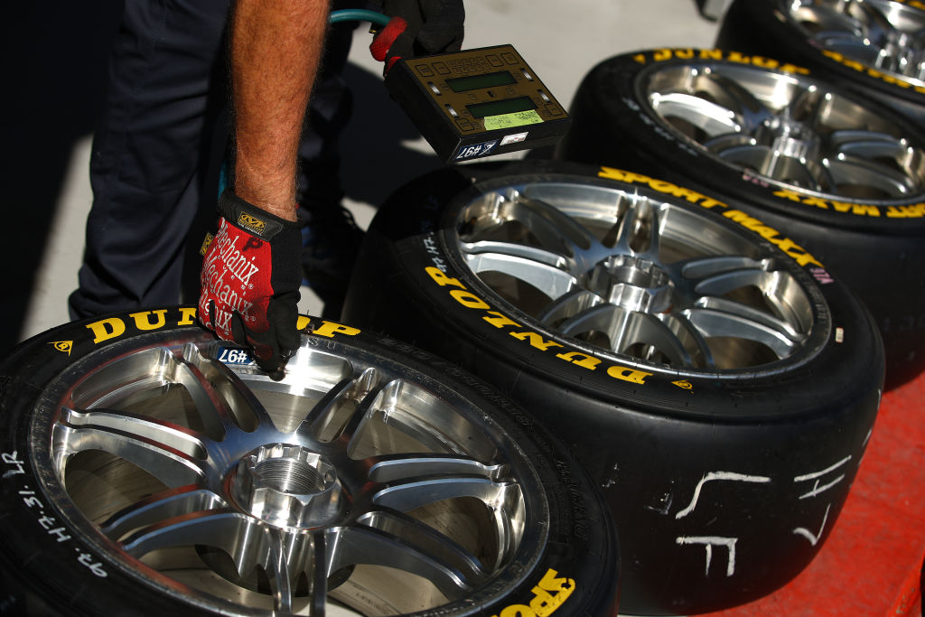 A crew member of the Red Bull Ampol Holden Commodore ZB checks tire pressure
