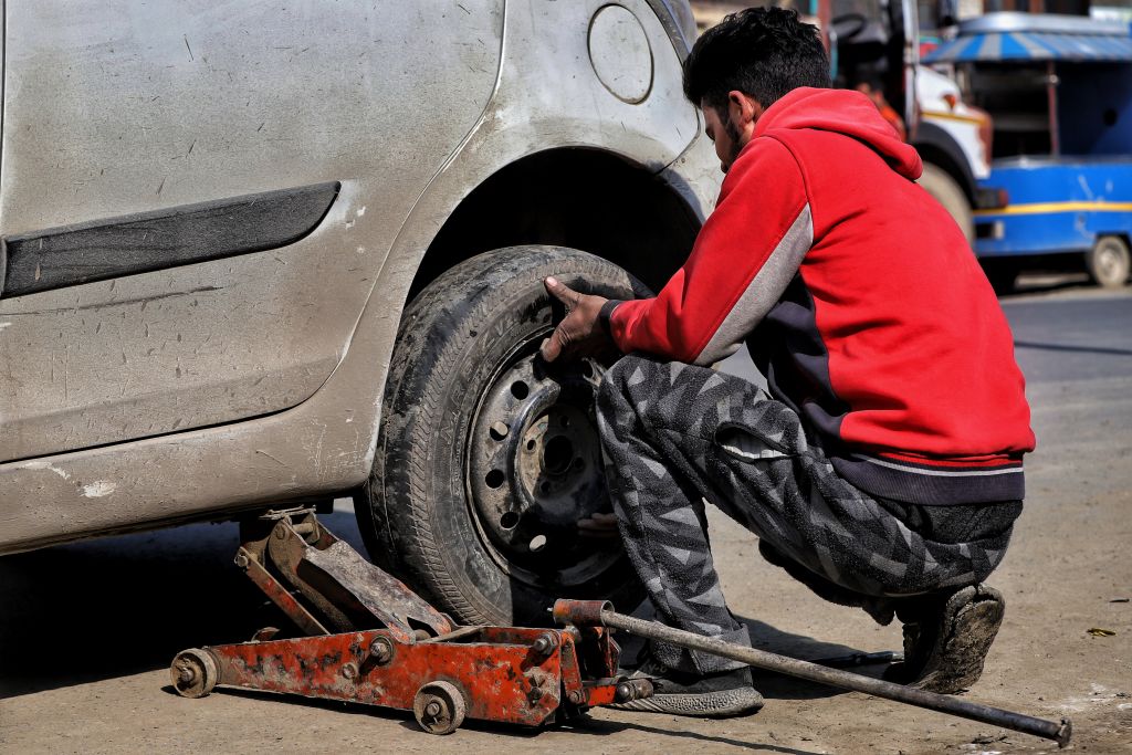 A man changes a dirty tire on the side of the road