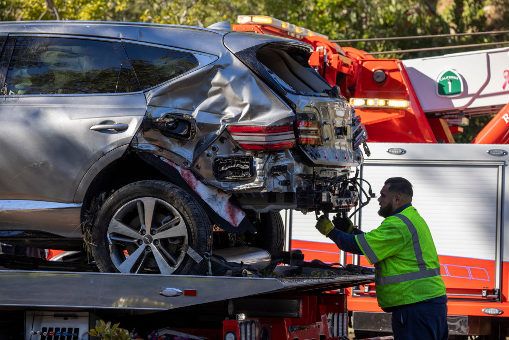 A tow truck operator secures the car that golf legend Tiger Woods was driving when seriously injured in a rollover accident