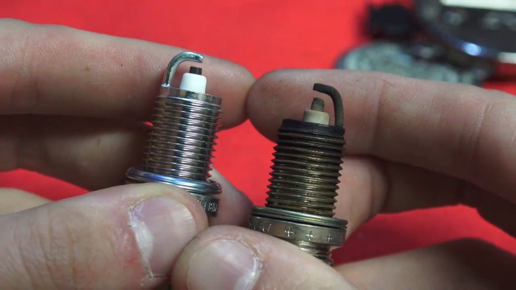 A good spark plug next to a worn spark plug