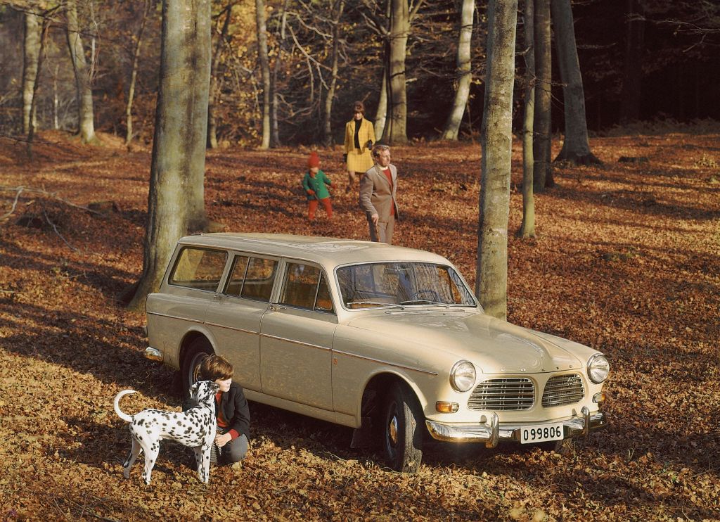 A family in a fall forest with a white 1962 Volvo 'P220' Amazon wagon