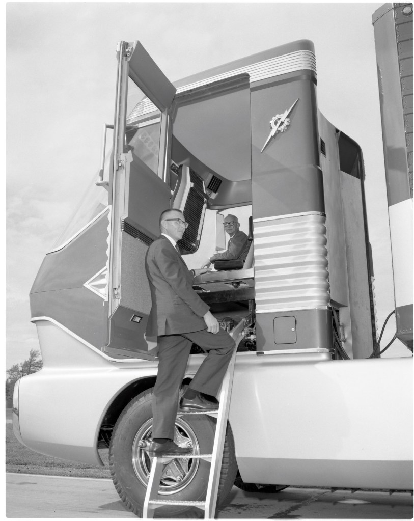 Two employees, one on the ladder and one inside the cabin of the 1964 Ford 'Big Red' gas turbine truck