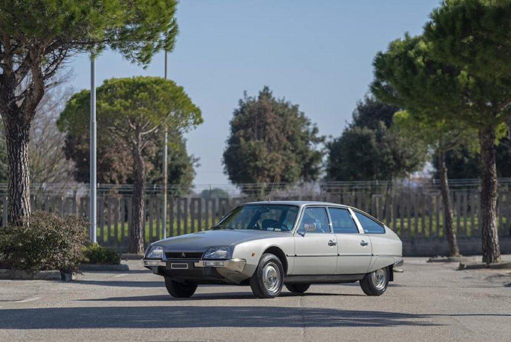A silver 1975 Citroen CX 2000 parked on a tree-lined driveway