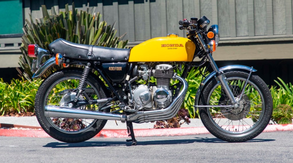 The side view of a yellow 1976 Honda CB400F Super Sport in a parking lot