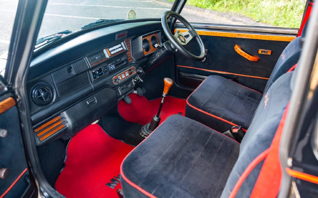 The red-and-black-velour-upholstered front seats and wood trim in a 1988 Rover Mini Jet Black Edition