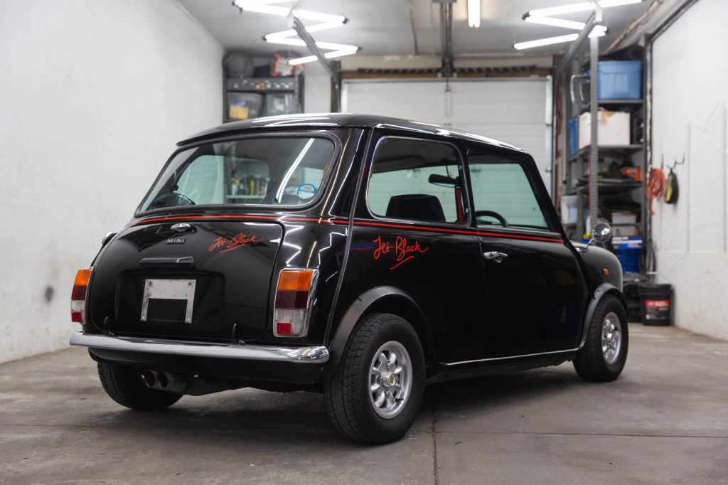 The rear 3/4 view of a black 1988 Rover Mini Jet Black Edition in a car workshop garage