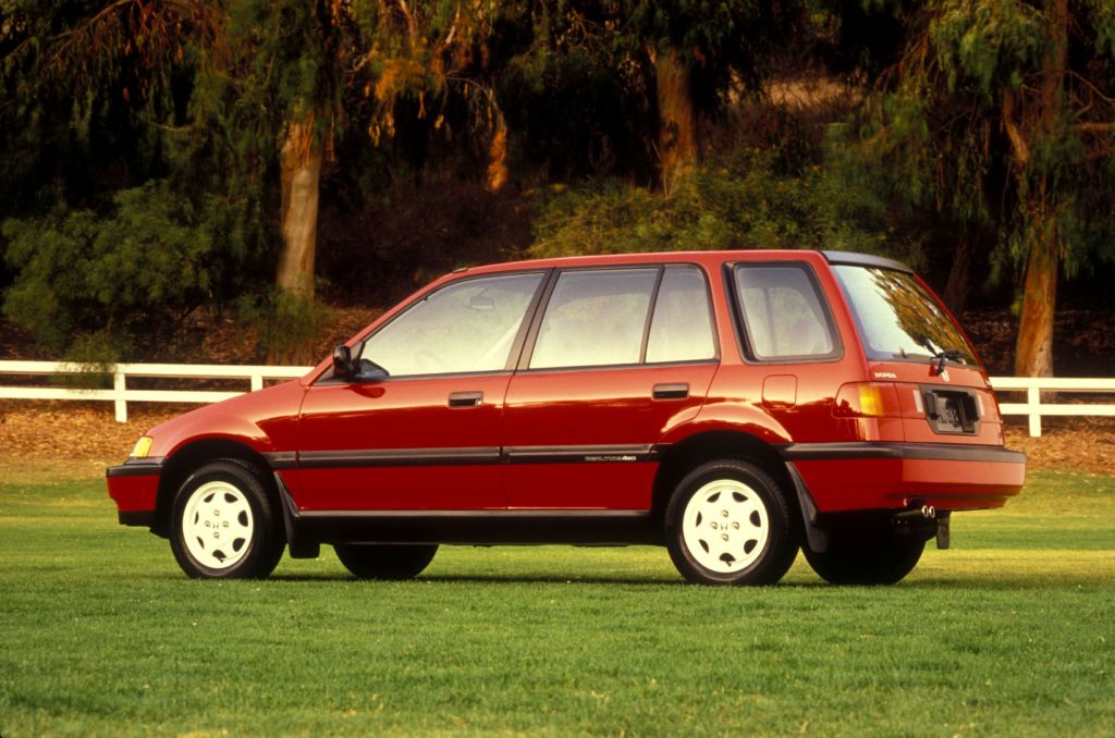 The side 3/4 view of a red 1989 Honda Civic 4WD Wagon in a grassy field