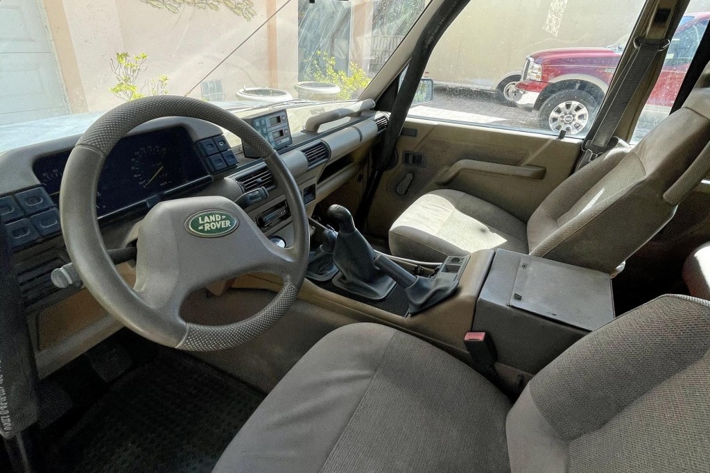 The tan-cloth front seats, tan dashboard, and front roll cage of a 1992 Land Rover Discovery Camel Trophy
