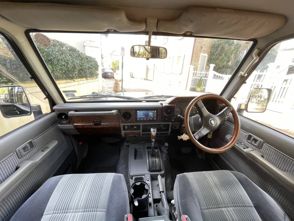 The gray-cloth front seats and black dashboard of a modified 1993 Toyota Land Cruiser Prado