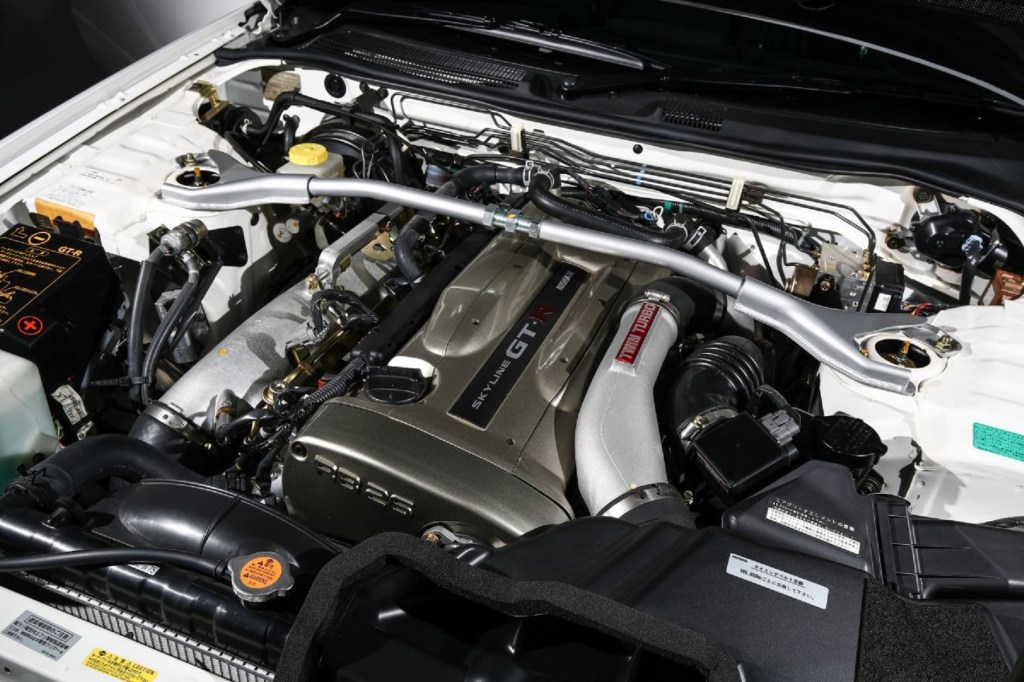 The engine bay of a white 2002 R34 Nissan Skyline GT-R V-Spec II Nur showing the gold engine cover