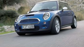 A blue 2006 'R53' Mini Cooper S drives down a valley road