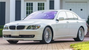 A white 2007 BMW Alpina B7 parked in the driveway of a white house
