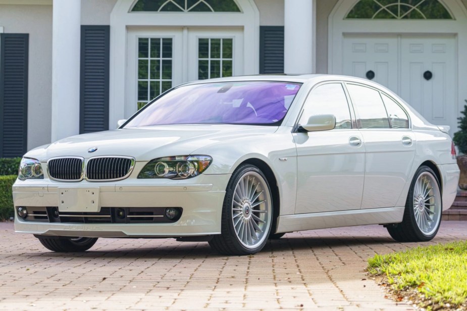 A white 2007 BMW Alpina B7 parked in the driveway of a white house