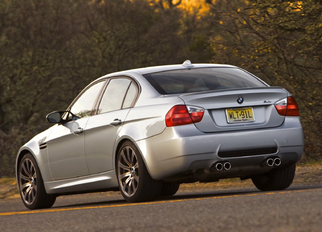 The rear 3/4 view of a silver 2008 E90 BMW M3 Sedan by some trees