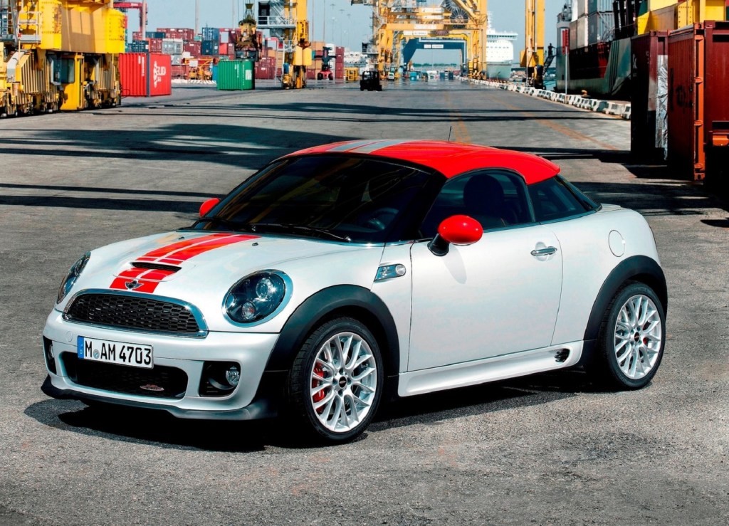 A white-with-red-roof 2013 Mini Cooper Coupe JCW on a shipping dock