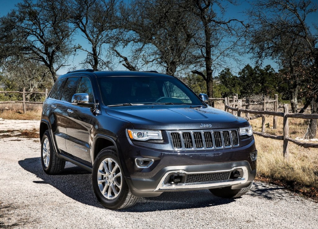 A dark-blue 2014 Jeep Grand Cherokee EcoDiesel Limited 4x4 parked by a plain forest