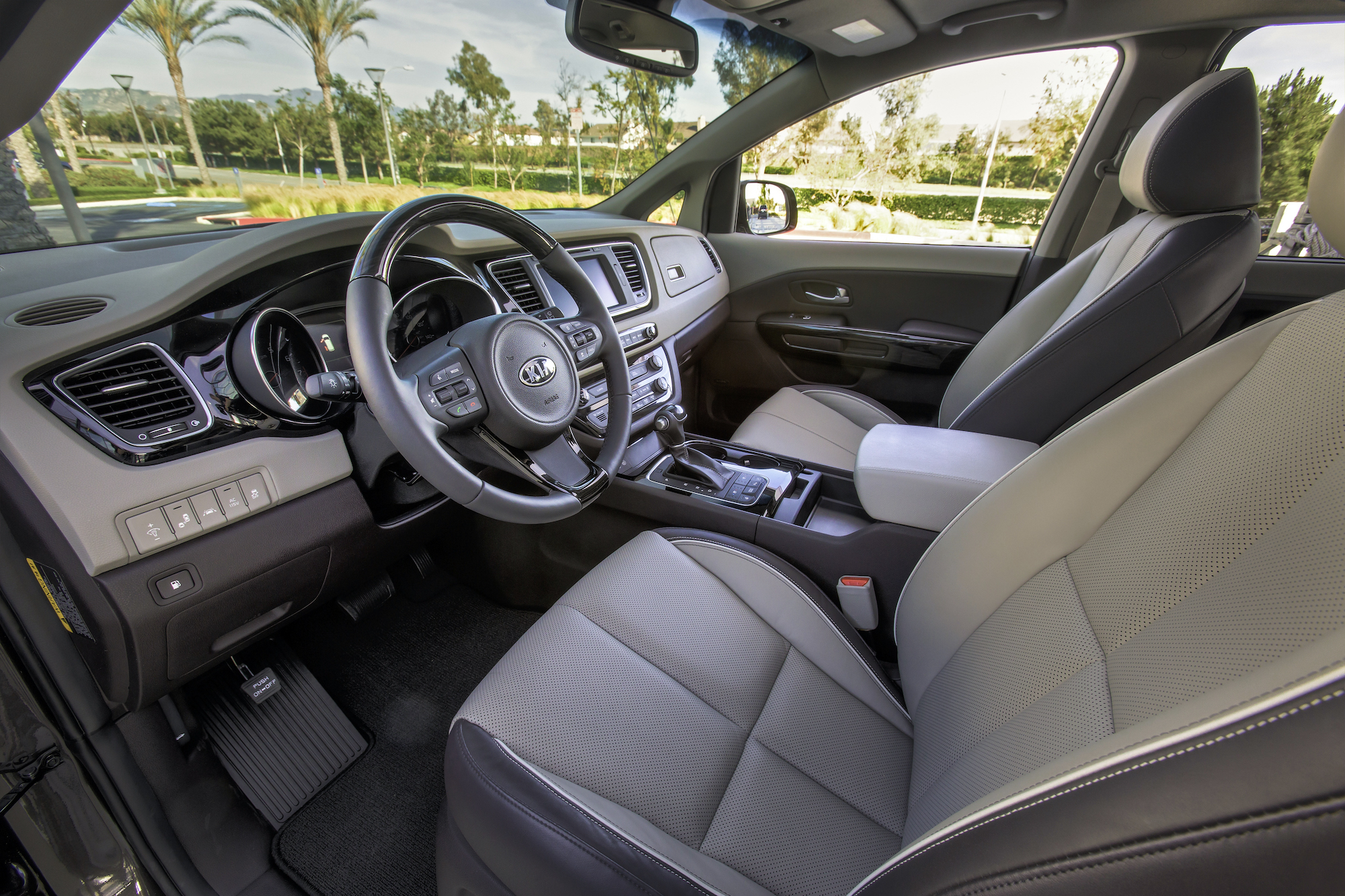 The light-gray front seats, steering wheel, and dashboard of a 2016 Kia Sedona minivan