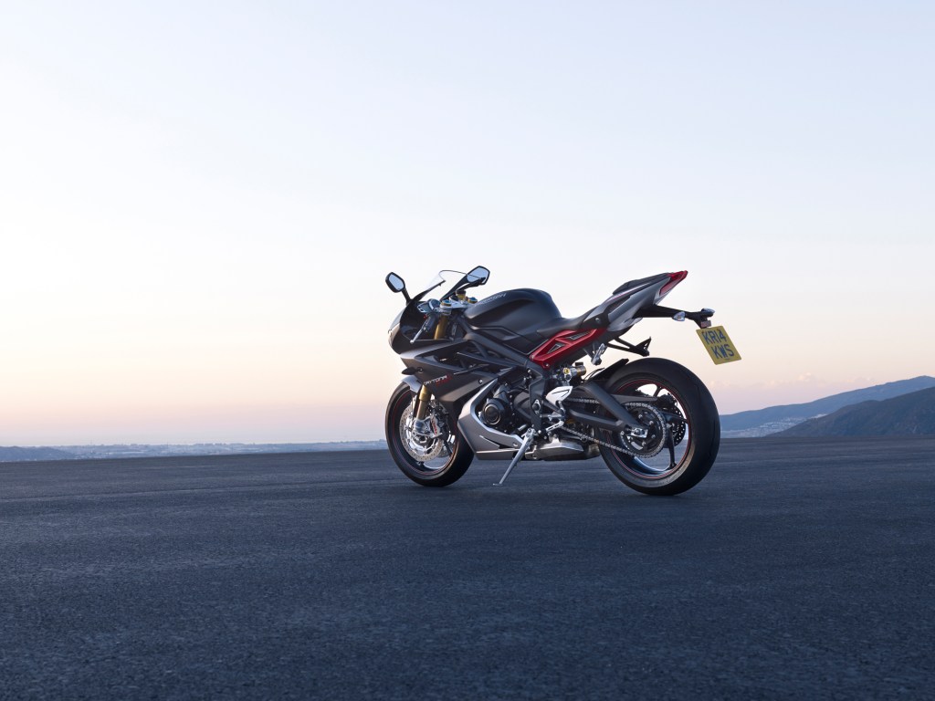 The rear 3/4 view of a black-and-red 2016 Triumph Daytona 675R on a mountainside parking lot