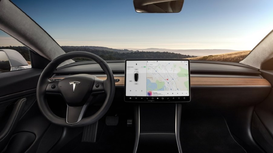 The black front seats and wood-trimmed dashboard of a 2018 Tesla Model 3