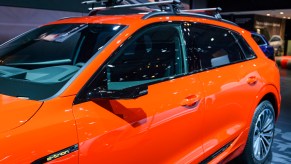 An orange 2020 Audi e-tron 55 Quattro all-electric luxury crossover SUV on display at Brussels Expo on January 9, 2020, in Brussels, Belgium