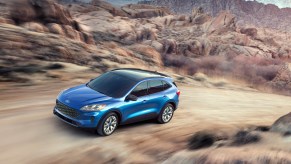 A blue 2020 Ford Escape compact SUV traveling on a dirt road up a mountain