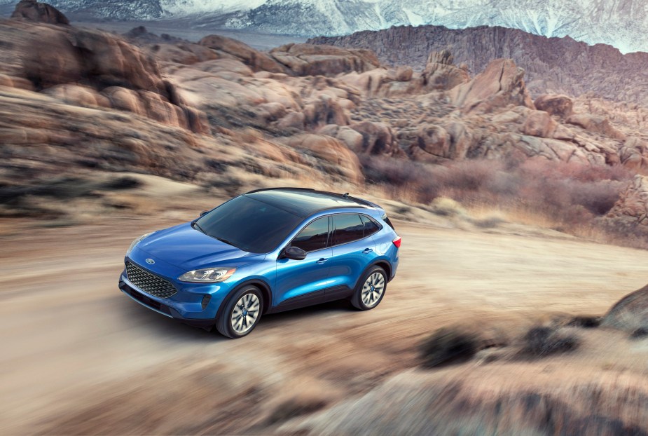 A blue 2020 Ford Escape compact SUV traveling on a dirt road up a mountain