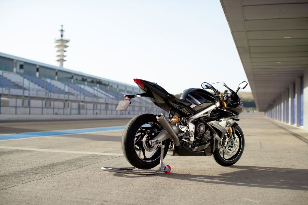 The rear 3/4 view of a black-and-silver 2020 Triumph Daytona 765 Moto2 Limited Edition on a rear-wheel stand at a racetrack