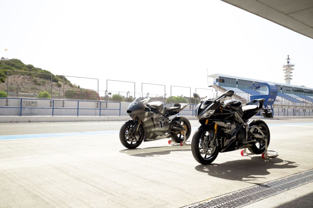 A black-and-silver 2020 Triumph Daytona 765 Moto2 Limited Edition parked next to the gray development mule on a racetrack
